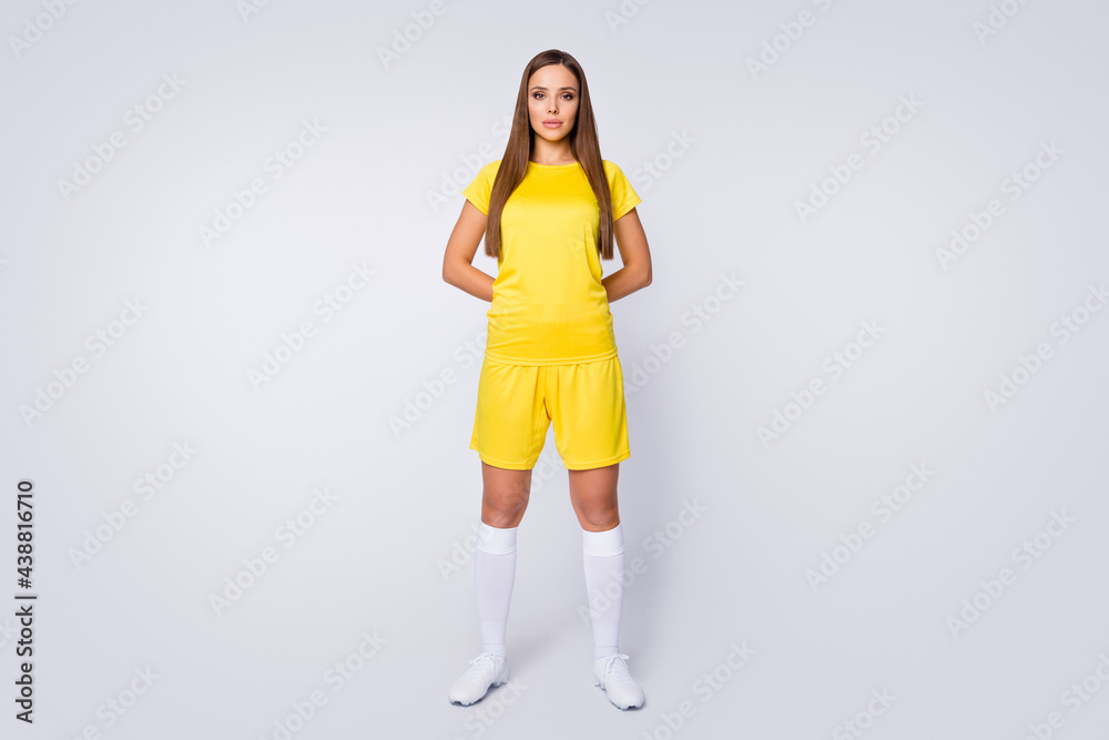 Full body photo of cool lady skilled player soccer team hold hands behind back wear yellow football uniform yellow t-shirt shorts socks shoes isolated white color background Full body photo of cool lady skilled player soccer team hold hands behind back wear yellow football uniform yellow t-shirt shorts socks shoes isolated white color background