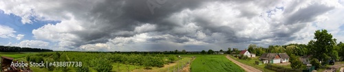 Panorama of sky with clouds and green field with garden