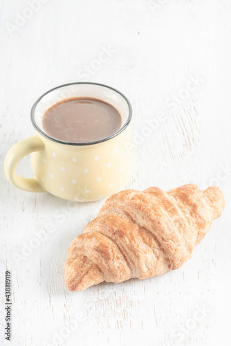 crispy croissants and cup of coffee on a wooden table