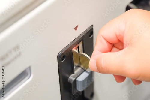 A asian man's hand inserting coin in to a vending machine slot machines ATM, Automatic Machine Technology for deposit or withdraw money business financial Background Concept