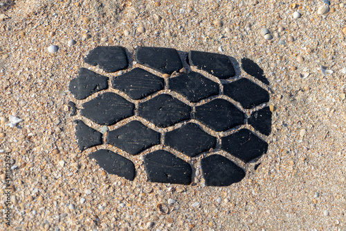 An image of an old car tire ingrown into the sand. Old car tire lying on the beach.