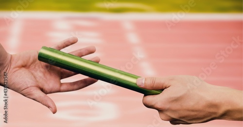 Composition of midsection of caucasian athletes passing green relay baton photo