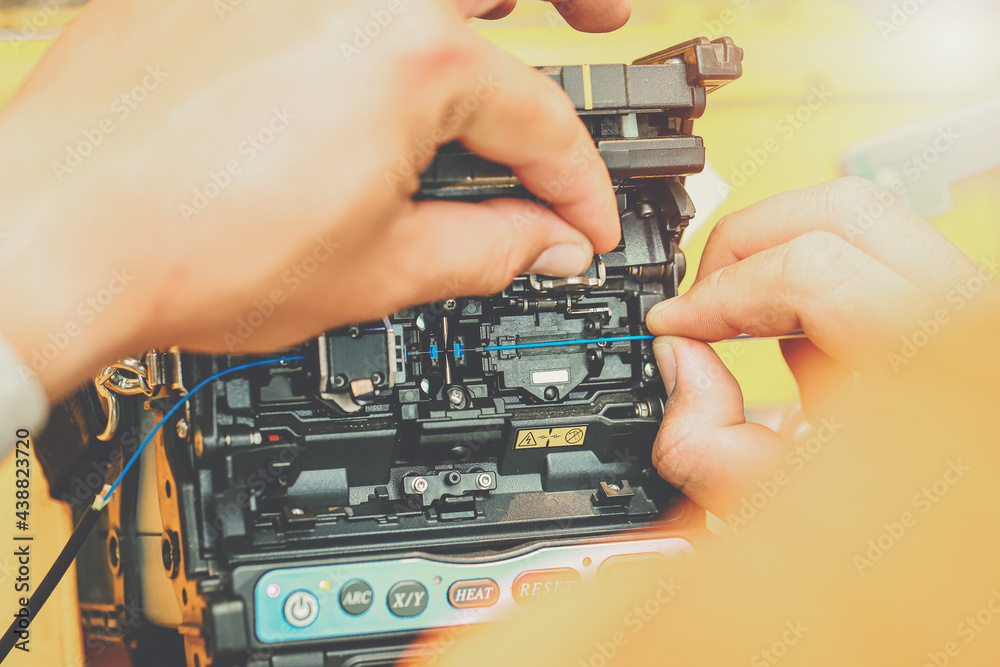 Technician Fiber optic cable network fusion splicing. Worker connecting for Cable Internet signal and Wire connection with Fiber Optic Fusion Splicing machine,classic tone effect. Technician Fiber optic cable network fusion splicing. Worker connecting for Cable Internet signal and Wire connection with Fiber Optic Fusion Splicing machine,classic tone effect.