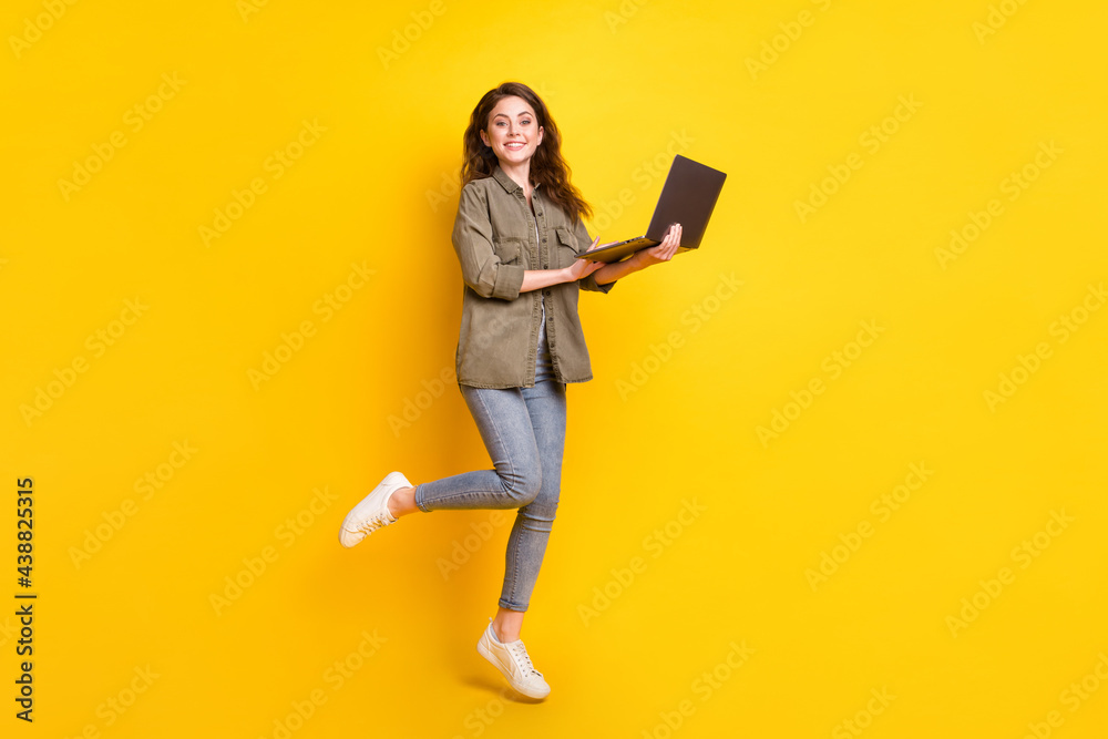 Full size portrait of cheerful person hands hold laptop look camera toothy smile isolated on yellow color background Full size portrait of cheerful person hands hold laptop look camera toothy smile isolated on yellow color background