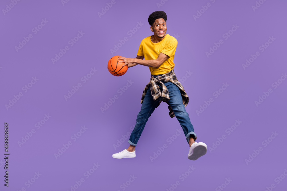 Full length body size view of attractive cheerful guy jumping throwing ball isolated over violet purple color background