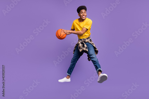 Full length body size view of attractive cheerful guy jumping throwing ball isolated over violet purple color background © deagreez