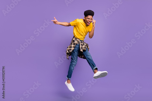 Full length body size view of attractive cheery cool guy jumping having fun showing mind isolated over violet purple color background