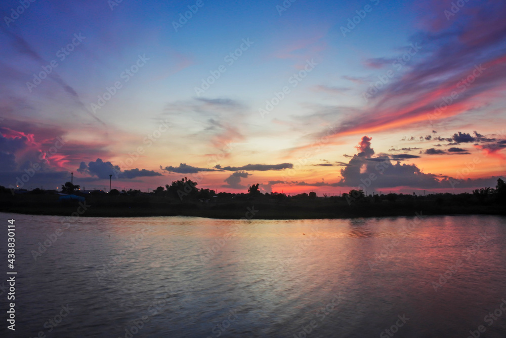 The rainy season sky, the evening sunset light, the sky and the clouds turn pink at the riverside beautifully.
