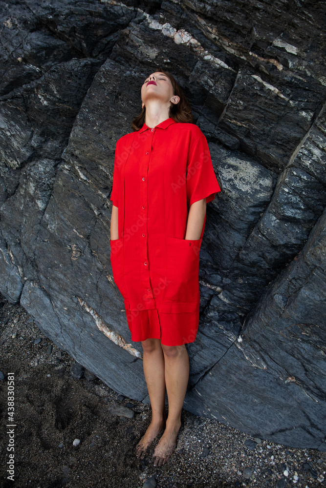 An elegant fashionable fresh beautiful woman in a red vintage dress with rocks background. An elegant fashionable fresh beautiful woman in a red vintage dress with rocks background.