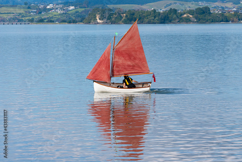 Traditional style red sails on small yacht becalmed in bay. photo