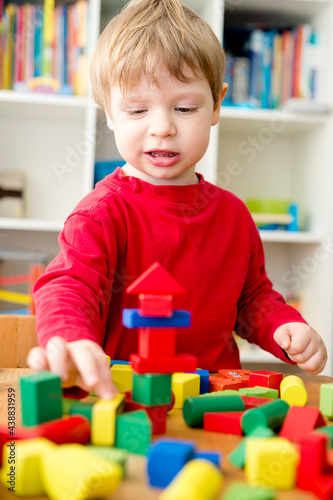 A young builder. Kids playing wooden blocks building tower and sort & stack toys. Kids Play Room. Development and Construction Concept.