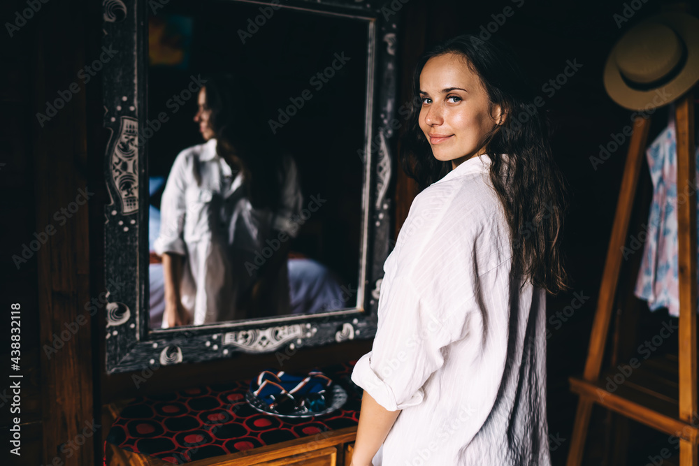 Content young woman standing in front of mirror in bedroom