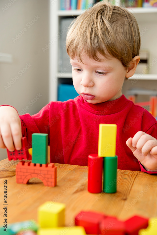 A young builder. Kids playing wooden blocks building tower and sort & stack toys. Kids Play Room. Development and Construction Concept. A young builder. Kids playing wooden blocks building tower and sort & stack toys. Kids Play Room. Development and Construction Concept.