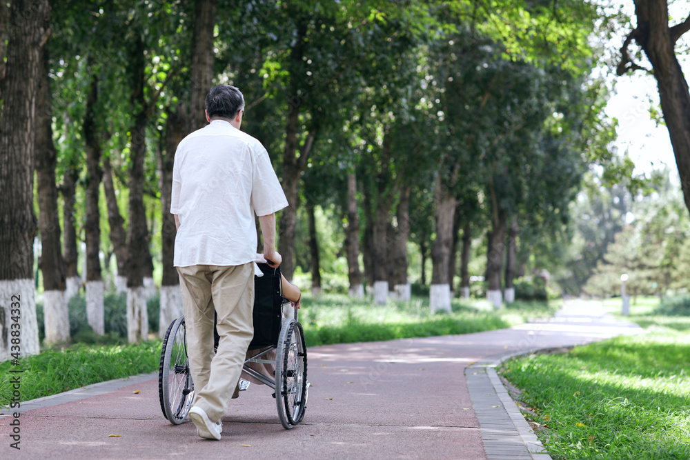 The old man pushes his wife in a wheelchair