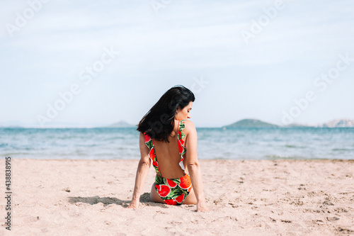 Woman sitting on sand looking at the beach. 