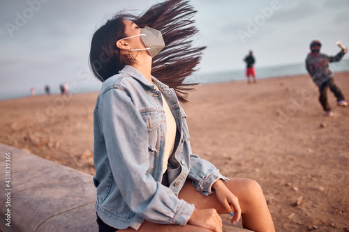 Mujer Joven latina mueve su cabello durante un bello atardecer.. personas con mascarilla 