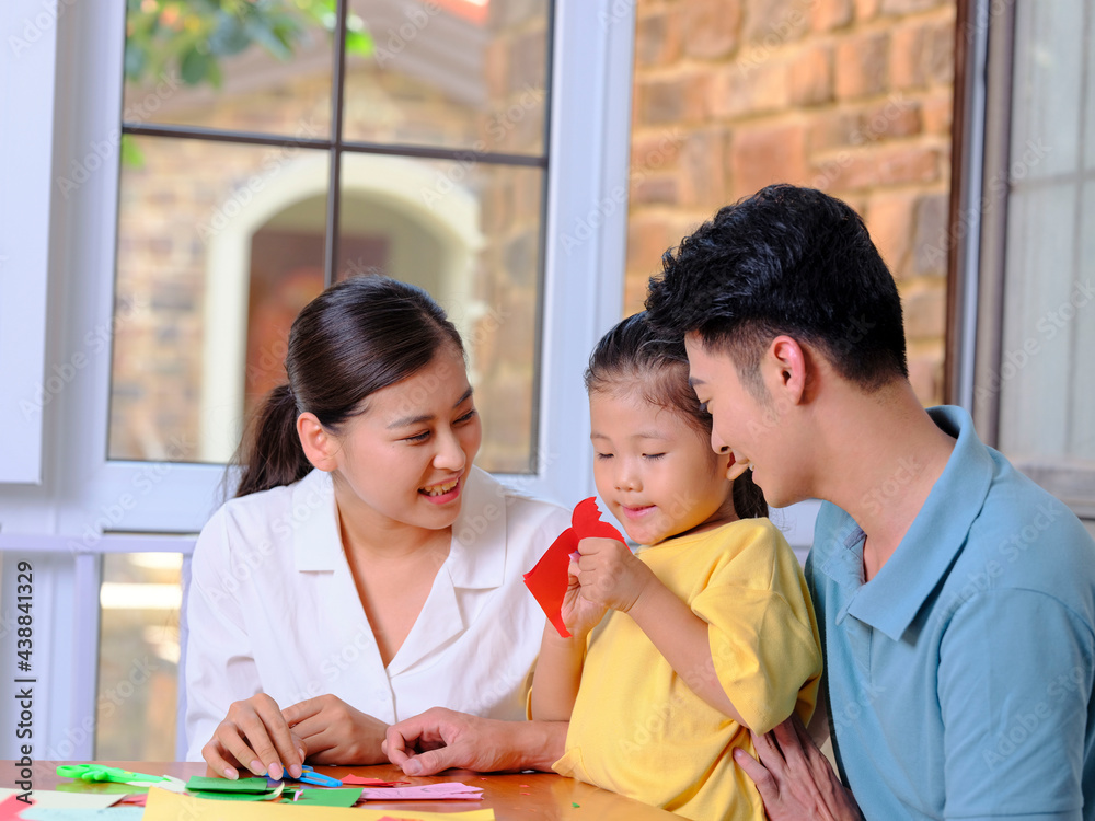 Obraz premium A happy family of three doing paper cutting in the living room