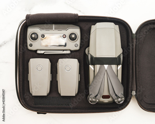 Folding drone quadcopter with full set in case. Top view or flat lay. Kit of drone UAV and accessories - controller and two battary in case over white marble background photo