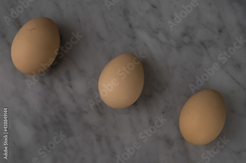 Three eggs arranged in a row on a marble table.