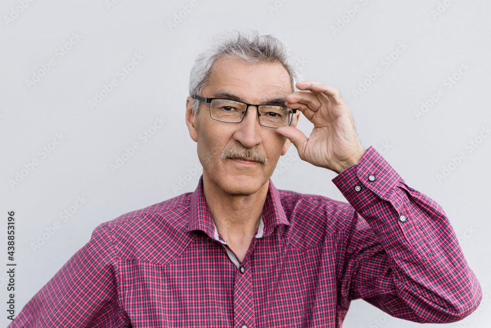 an elderly man of 60s wearing glasses for vision on a gray background. the concept of eye health in the elderly. portrait of an old man an elderly man of 60s wearing glasses for vision on a gray background. the concept of eye health in the elderly. portrait of an old man