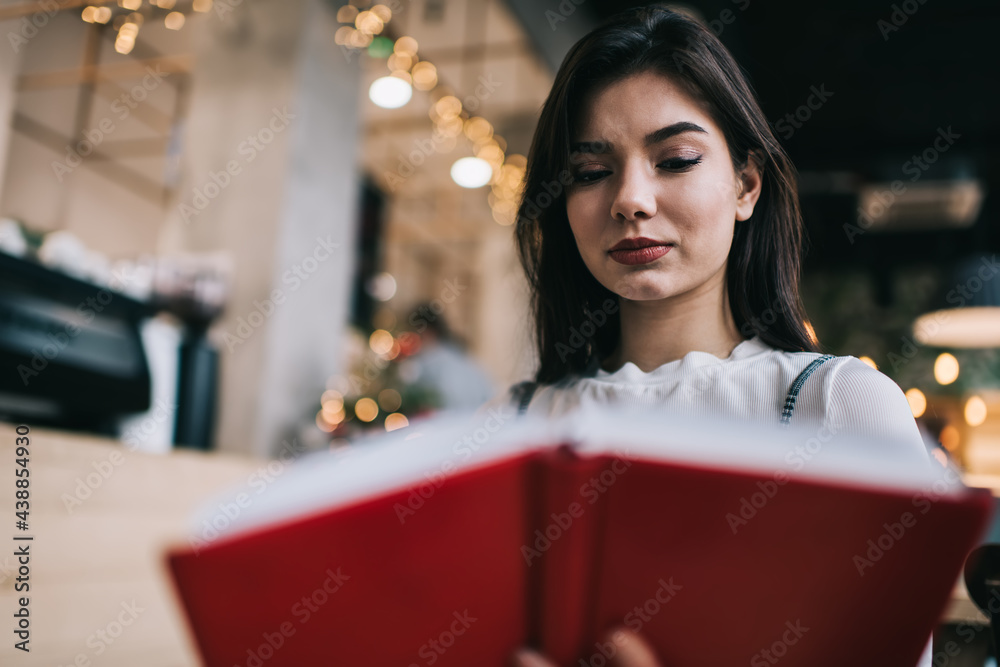 Calm woman reading copybook and studying
