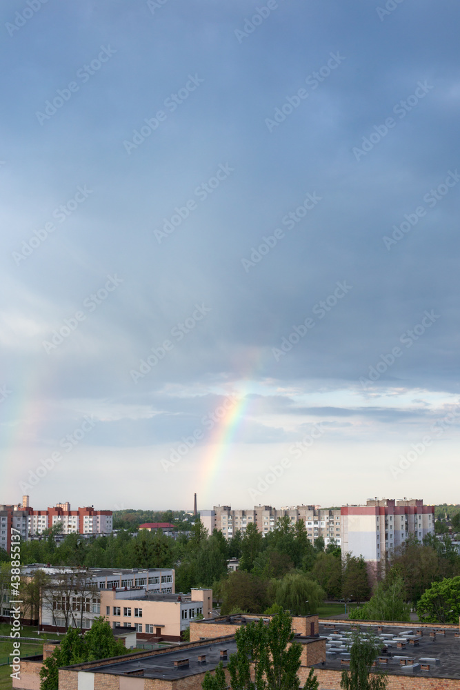 Bright rainbow against the background of a contrasting sky over the city