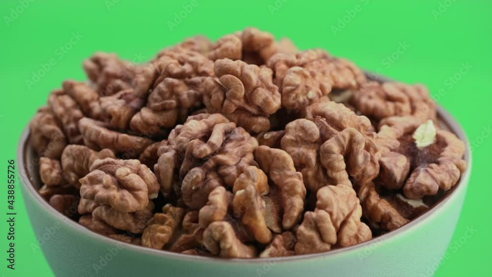 Peeled walnut in a bowl rotate on their axis, isolated on a green screen background, chroma key. Walnut grains close-up. Template for motion design or advertising. Walnut kernels. Peeled walnut in a bowl rotate on their axis, isolated on a green screen background, chroma key. Walnut grains close-up. Template for motion design or advertising. Walnut kernels.
