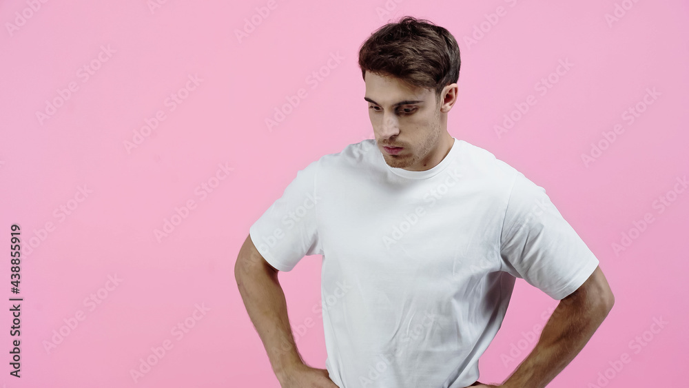 Thoughtful man in white t-shirt standing isolated on pink Thoughtful man in white t-shirt standing isolated on pink