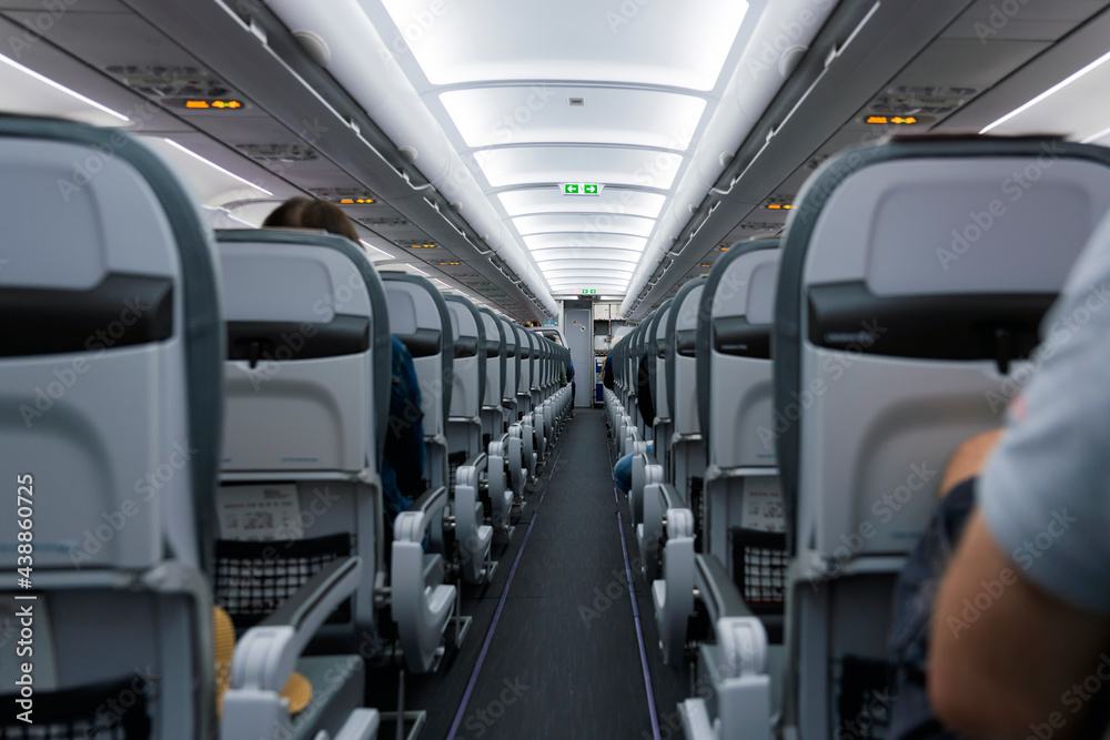 (Selective focus) View of an aircraft cabin with passengers ready for departure. Night flying, concept of travel during the Covid-19, Coronavirus pandemic.