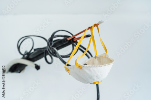 The construction mask dangles from a piece of wire sticking out of the wall. Respiratory protection for interior decoration and painting of premises. Close-up