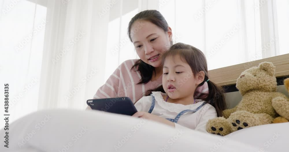 mother and daughter are playing together on the bed (looking to tablet) 3 mother and daughter are playing together on the bed (looking to tablet) 3