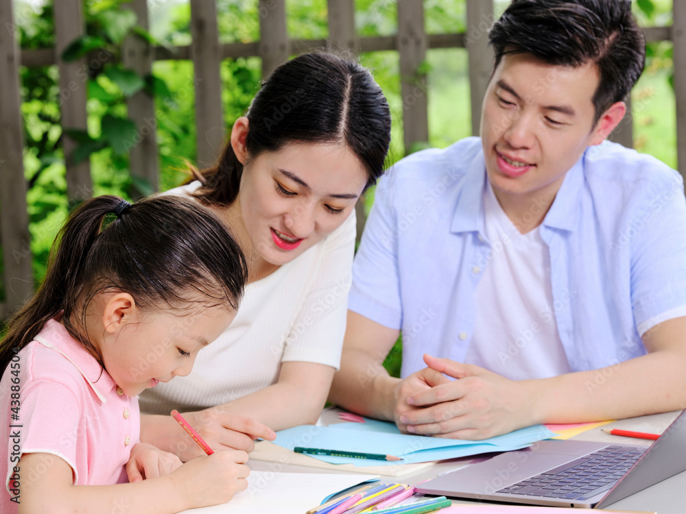 Young parents help their children with their homework outdoors Young parents help their children with their homework outdoors