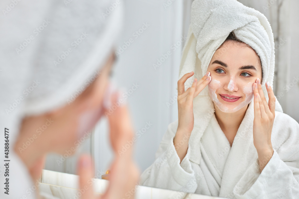 woman in white bathrobes applying apply facial cream woman in white bathrobes applying apply facial cream
