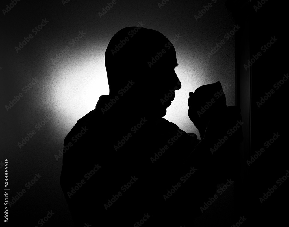 Silhouette of a man putting on a mask