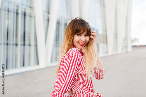  Close up portrait of Happy woman in red dress posing on the street.