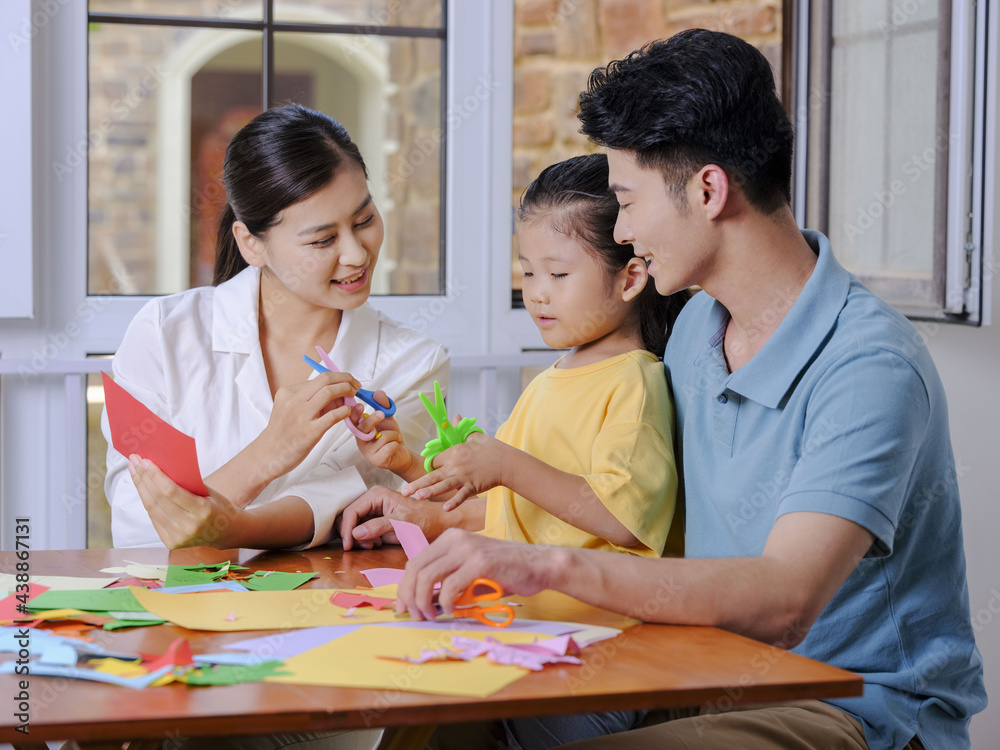 © eastfenceimage - A happy family of three doing paper cutting in the living room © eastfenceimage - A happy family of three doing paper cutting in the living room