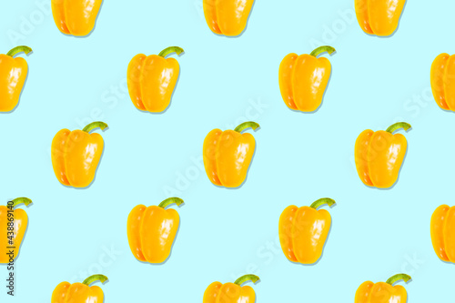Fototapeta Naklejka Na Ścianę i Meble -  Seamless pattern of whole yellow peppers with a green branch on a blue background