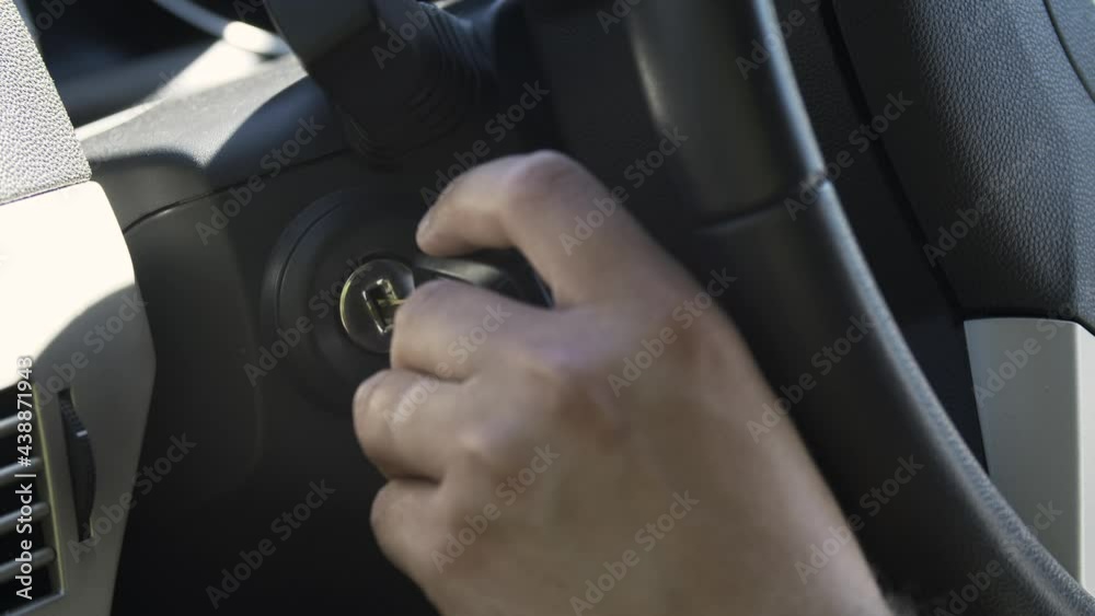 Close up male hand inserts key into the ignition lock. Right-hand drive car