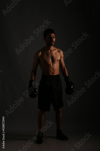 Young strong boxer fighting in shadows