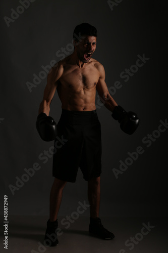 Young strong boxer fighting in shadows