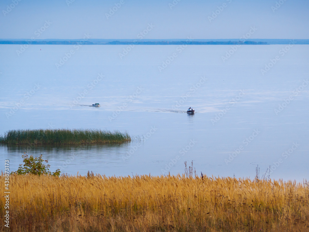 Two boats sails to the shore, evening at the mouth of the Kama River, which flows into the Volga River, Republic of Tatarstan, Russia. Two boats sails to the shore, evening at the mouth of the Kama River, which flows into the Volga River, Republic of Tatarstan, Russia.
