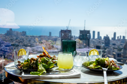 Caesar salad in two plates on a round table in a restaurant or cafe with a panoramic window on a sunny day