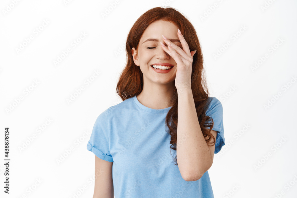Carefree smiling redhead woman, touching natural no makeup skin, close eyes and look happy, daydreaming, remember beautiful memories, standing over white background Carefree smiling redhead woman, touching natural no makeup skin, close eyes and look happy, daydreaming, remember beautiful memories, standing over white background