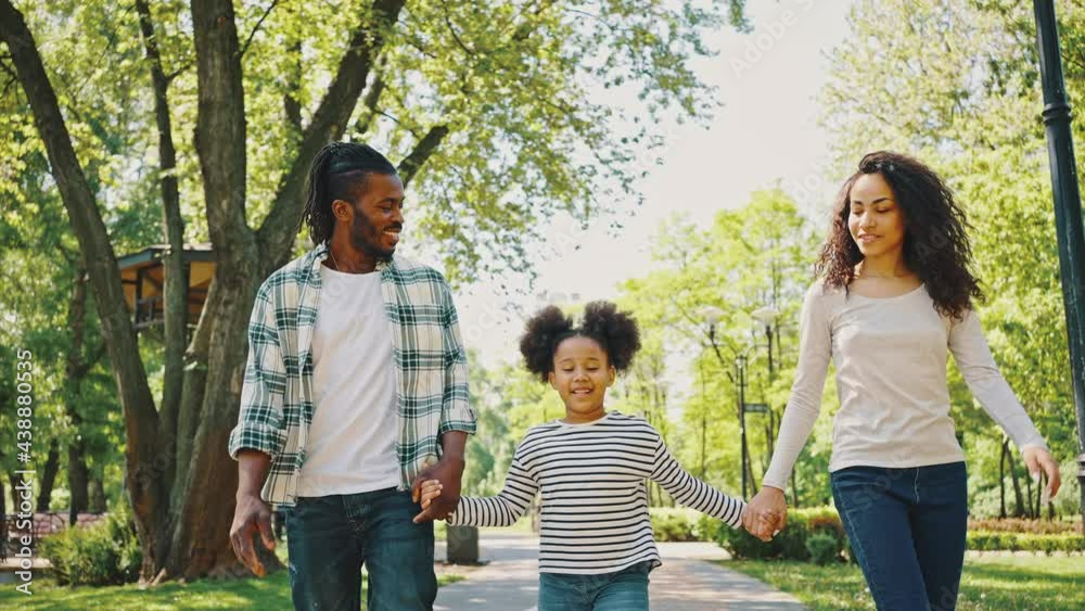 Cloce up African American family walking in the park holding hands and smiling. Have fun during a family weekend Cloce up African American family walking in the park holding hands and smiling. Have fun during a family weekend