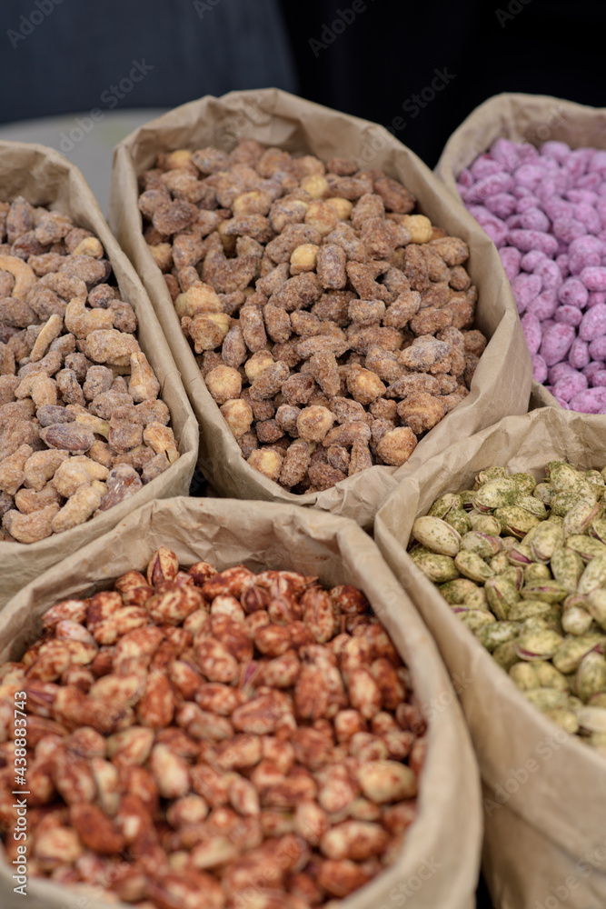 Fototapeta premium Almonds and pistachios with spices lie in paper bags on the counter.
