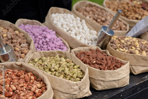 Almonds and pistachios with spices lie in paper bags on the counter.