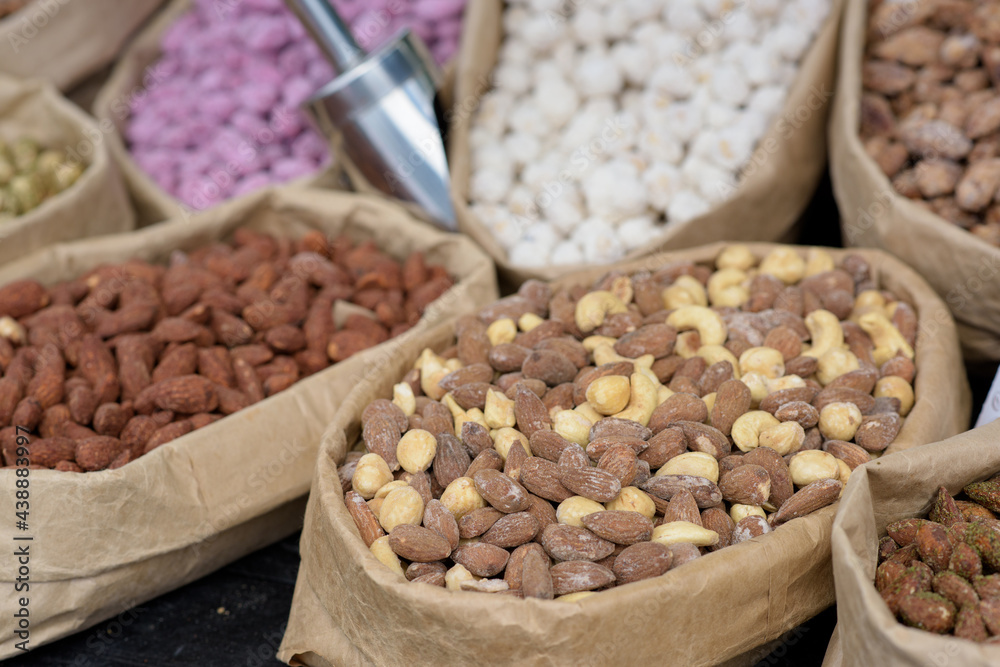 Fototapeta premium Almonds and pistachios with spices lie in paper bags on the counter.