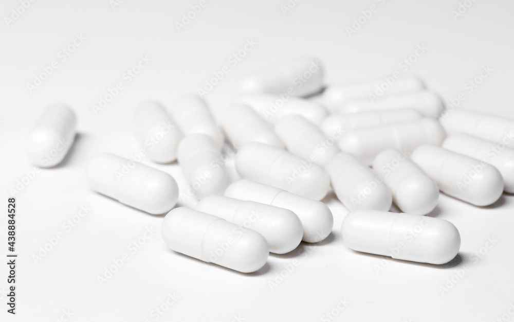 a lot of white pills are lying on the white table. Health and Medicine Concept. High quality photo a lot of white pills are lying on the white table. Health and Medicine Concept. High quality photo
