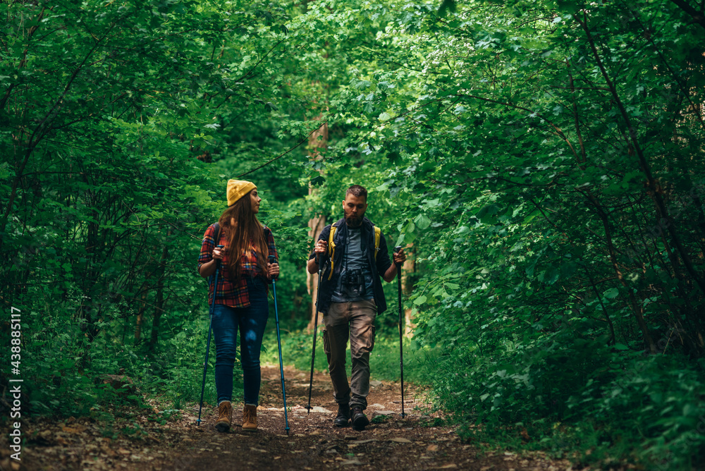 A young couple of hikers using trekking poles and wearing backpacks A young couple of hikers using trekking poles and wearing backpacks