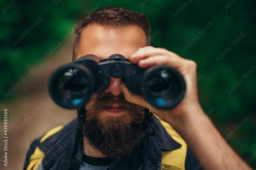 Hiker man using binoculars while watching birds in nature Hiker man using binoculars while watching birds in nature